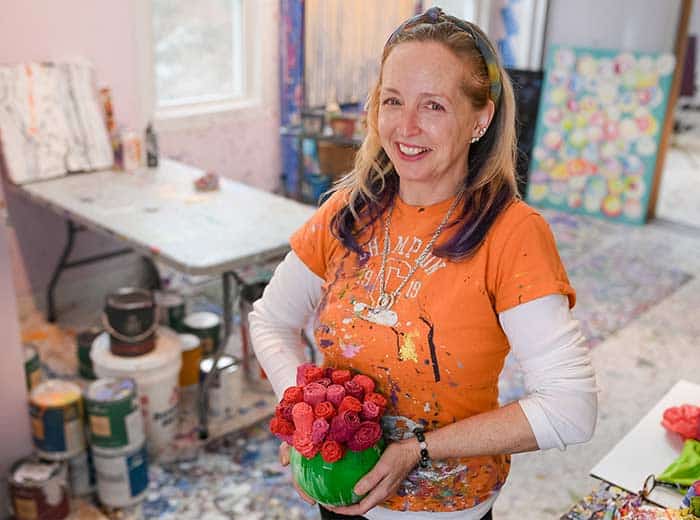 Jilma Sweeney artists holding a bouquet of red sponge "roses" in a green vase